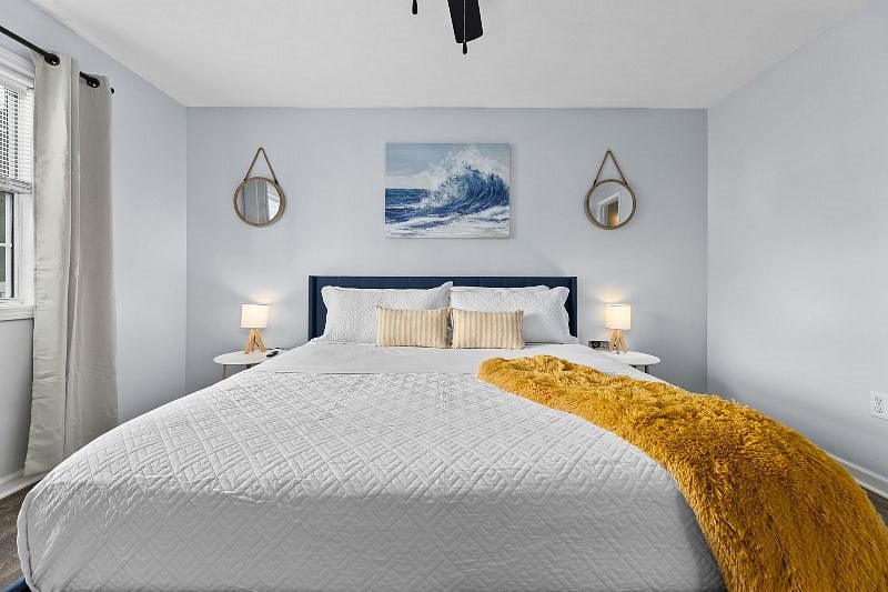 Warm and inviting main bedroom with a comfortable king-size bed, alarm clock, 32-in smart tv, closet with storage, and ceiling fan