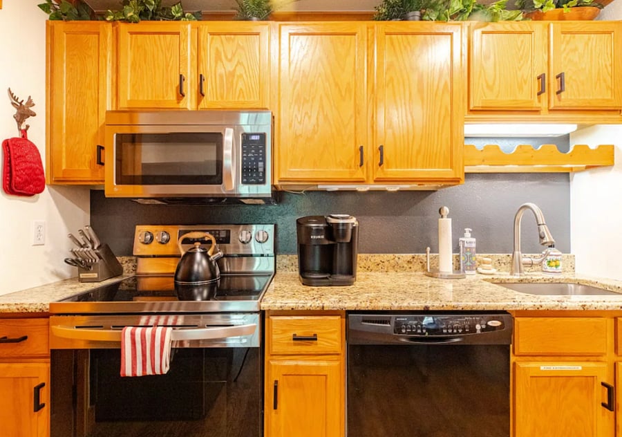Kitchen with microwave, dishwasher stove top oven, refrigerator, coffee maker, tea kettle, sink, dining area, cabinets fully stocked with everything you need to cook most meals.