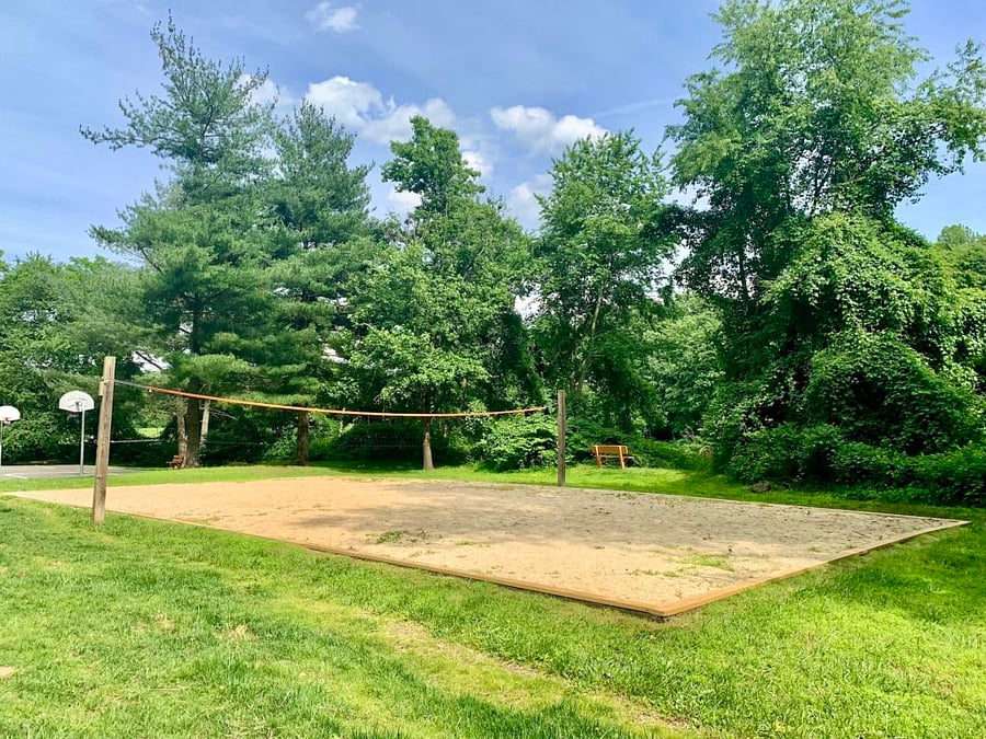 Park behind house has large grassy areas, basketball and volleyball courts