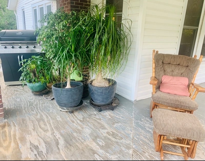 Covered porch with large gas grill, rocking chair, and outside dining table