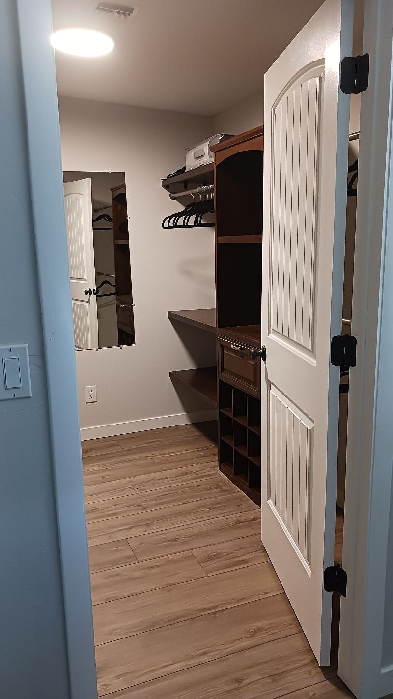 Walk in closet, both sides lined with shelves and hanging racksWash