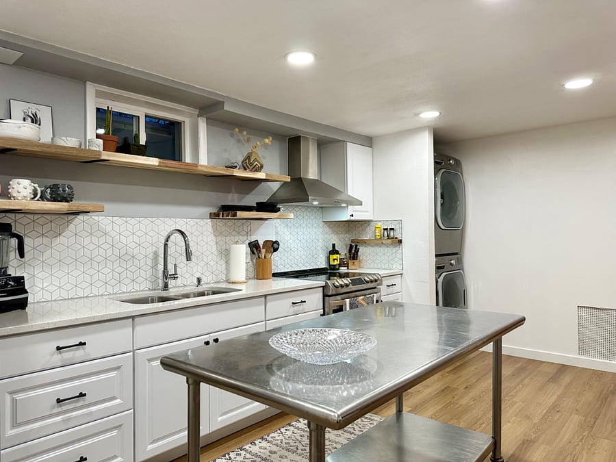 Kitchenette features modern backsplash with geometric shapes. Soft close cabinets and a stainless steel rollaway table.