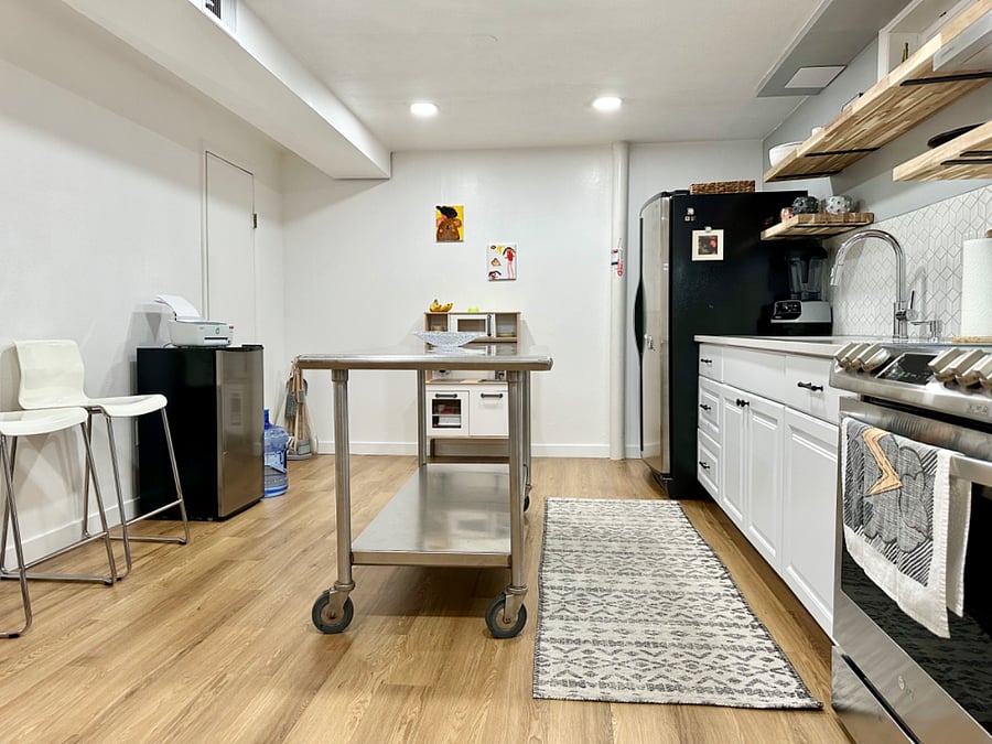 Open space with two prep surfaces, stainless steel table, or quartz counter tops. 