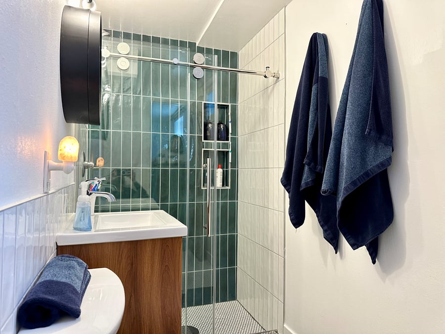 Sliding glass shower door, emerald green subway tile and a penny tile shower base. 