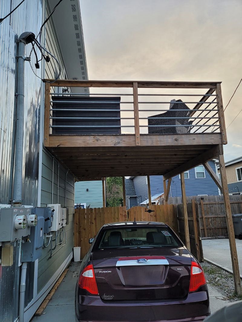 View from alley to carport/deck. We do keep our trash bins near the front right corner of the picture, otherwise the deck and parking are yours! We have since added a ring camera mounted to the post on the hinge side of the gate. A ring floorlight is also mounted on the front of the garage. Additional motion lights have also been added based on feedback from guests.