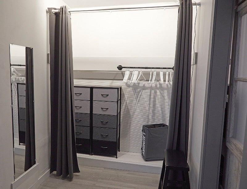 Expansive closet with drawers, hanging rack, curtain "doors," and full-sized mirror.