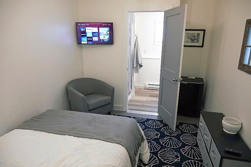 Bedroom with "en suite" bathroom, additional storage drawers, comfy accent chair, and 32 inch Smart TV.