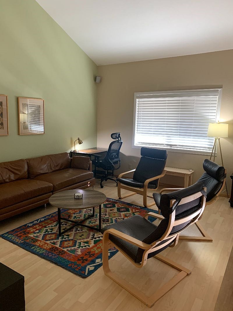 Living room with large couch, desk, easy chairs and TV