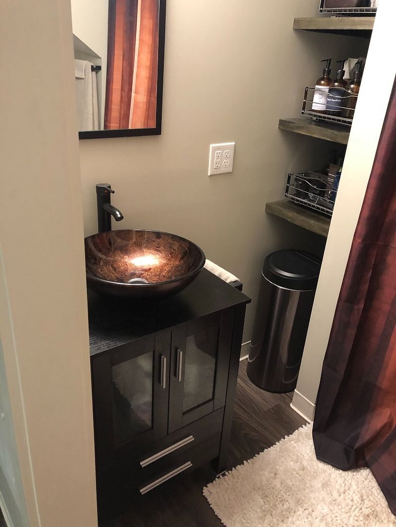 The bathroom has a vessel sink and a bluetooth speaker in the shower.