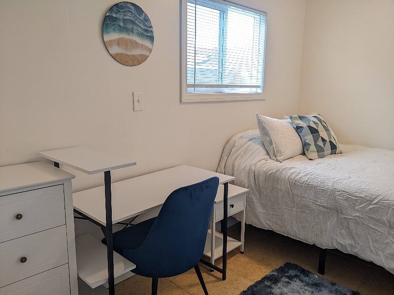 Smaller bedroom with double bed, desk, and dresser.