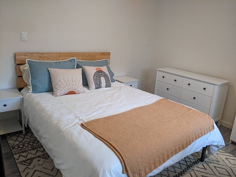 Large bedroom with queen bed, dresser, wardrobe, and desk.