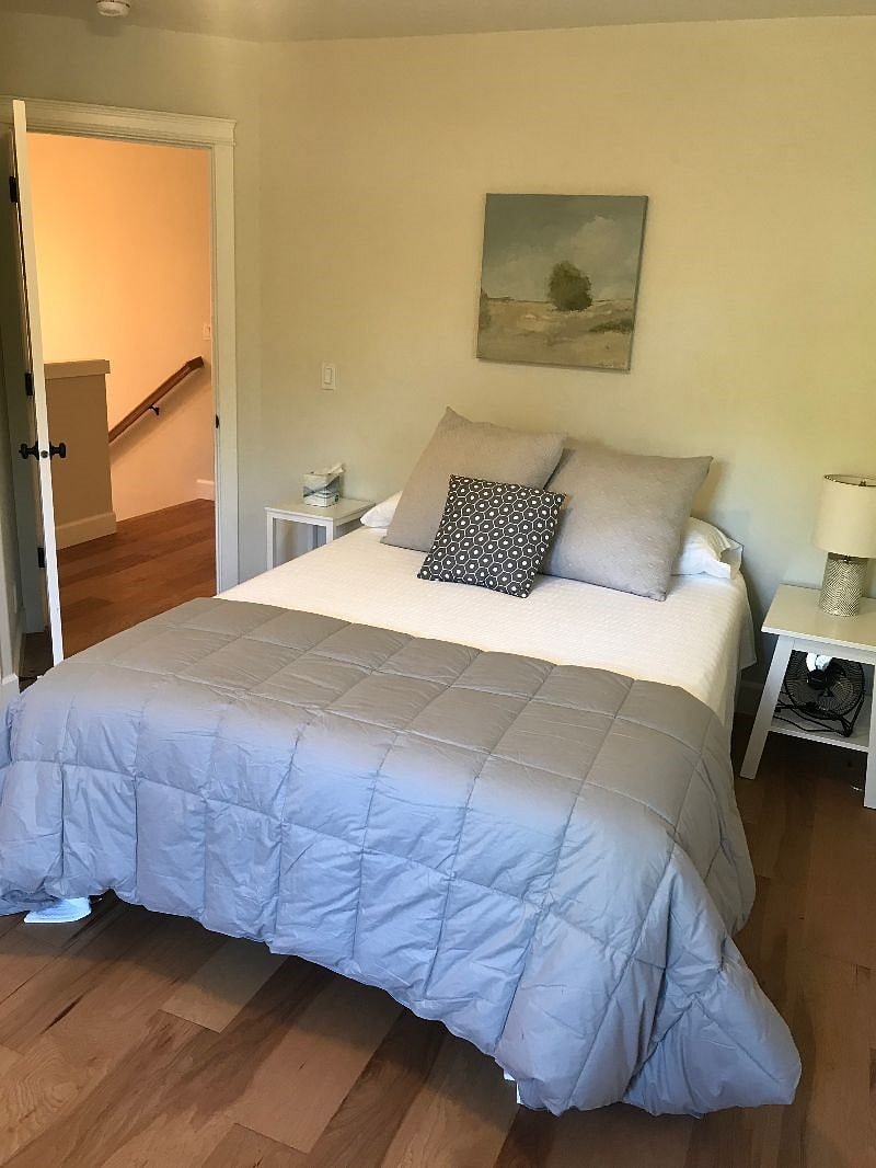 Upstairs bedroom #1 with queen bed. Full closet with hangers, a 3 drawer white dresser, and suitcase stand.