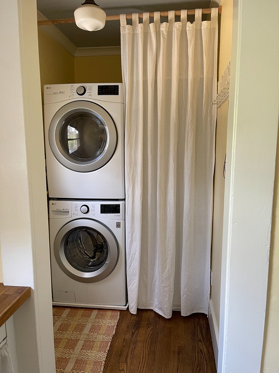 Laundry room washer and dryer. Cleaning supplies behind curtain.