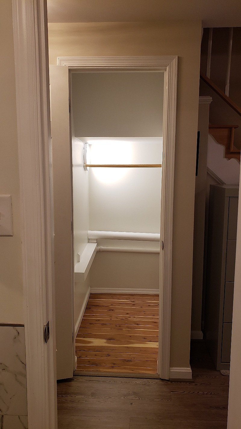 Additional under-stairs storage with light and hanging rod.