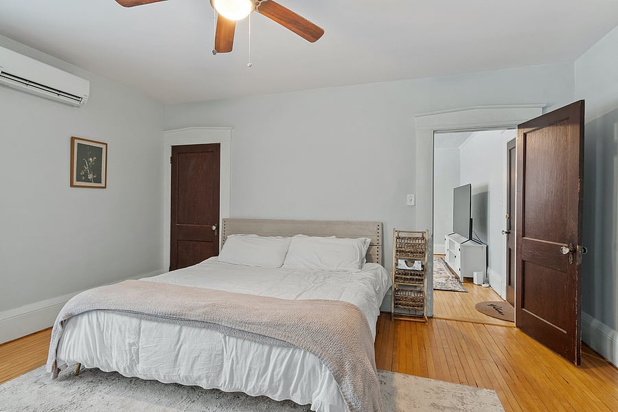 Spacious bedroom with a king-size bed, floor-to-ceiling windows, dresser, desk, and full-length mirror. Perfect for restful nights and comfortable work-from-home setup with plenty of natural light.
