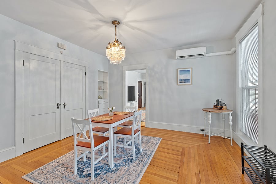 Bright, elegant dining area with a chandelier, floor-to-ceiling windows, and a stylish bar cart. Perfect for meals, entertaining, or enjoying a glass of wine while taking in the view.