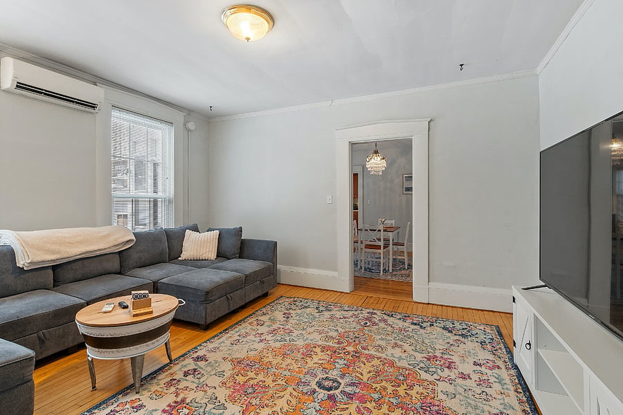 Bright, airy living room with a huge couch, TV, and floor-to-ceiling windows. Ideal for unwinding, entertaining, or soaking in sunlight throughout the day.