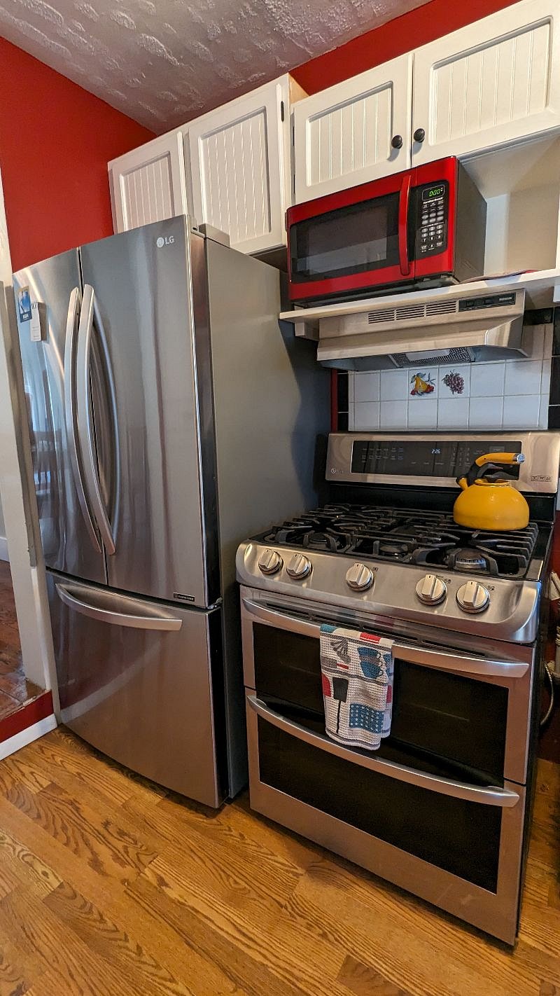 kitchen with double oven and gas stove top, large refrigerator, tea kettle.