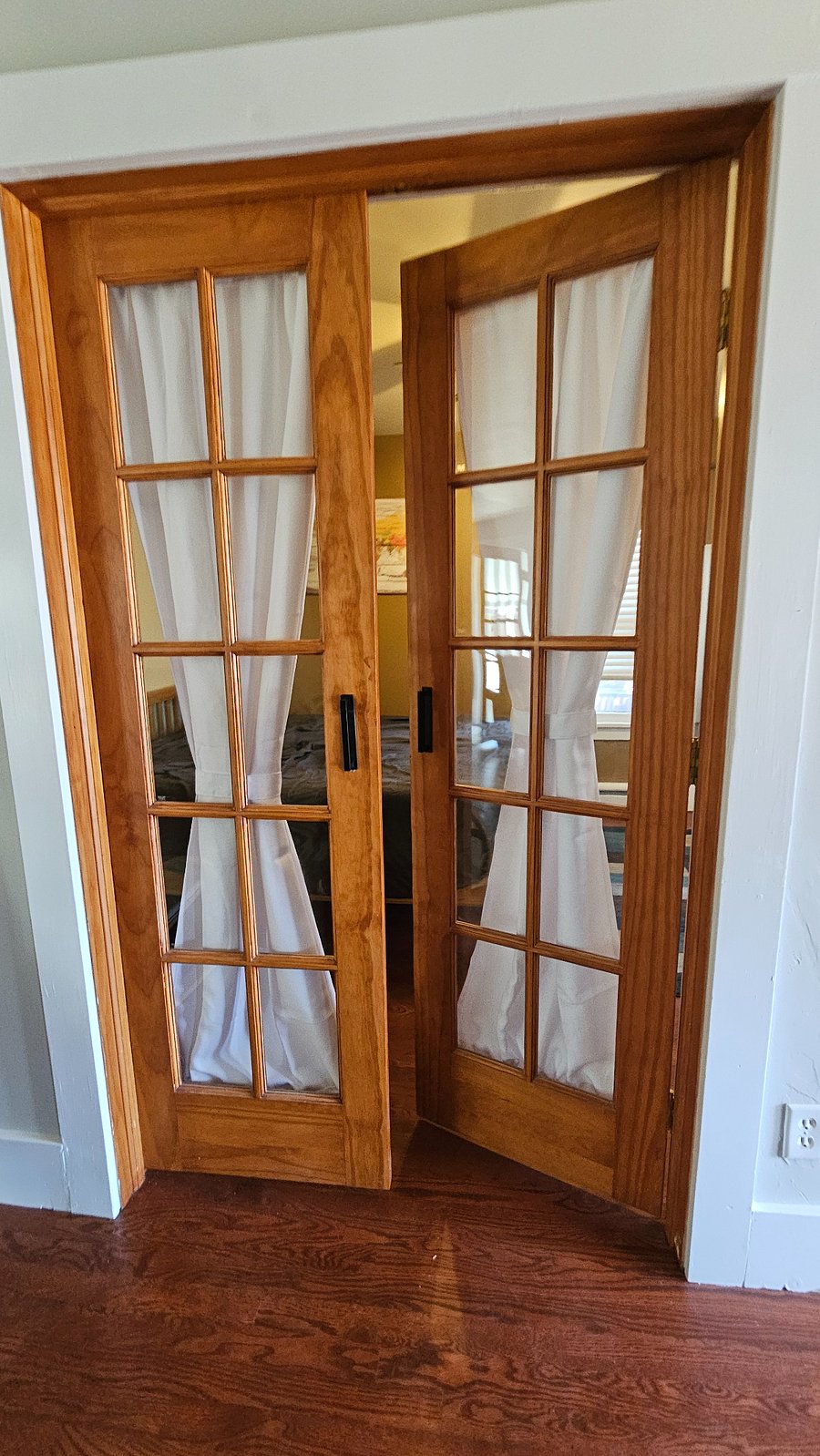 French doors with curtains leading to front bedroom next to living room.