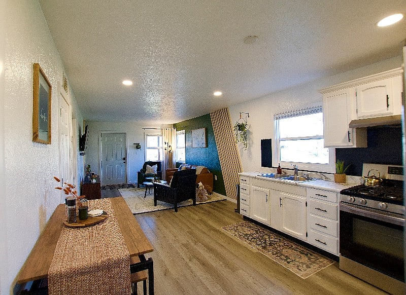 The view of the kitchen & living room standing by the bathroom door.