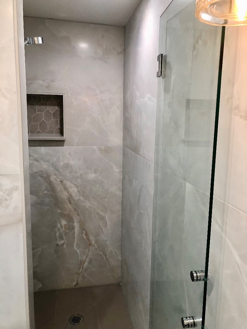 Tiled bathroom with stall shower; door swing open in both directions