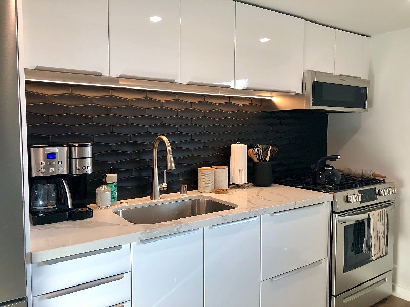New kitchen with tiled backsplash, dishwasher, gas range, microwave/range hood