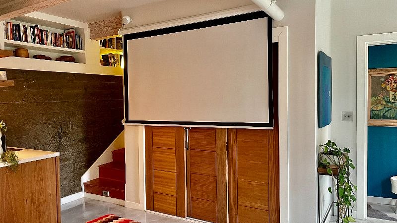 A projector, pull-down screen, and surround-sound speakers turns the bottom floor into a media room.