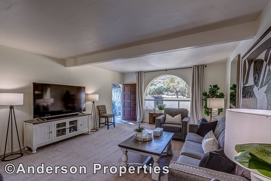 Large Living Area with 60 inch smart TV and surround sound system. Picturesque arched window looks out onto courtyard and Large Cactus.   