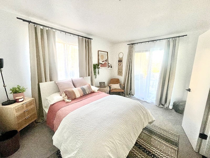 Room has window behind bed and sliding glass door to shared balcony with screen, door and table and chairs.