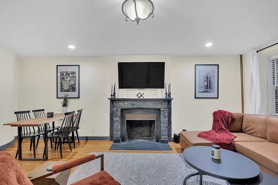 This open-concept living room is the heart of the home, featuring a large, cozy couch and plenty of seating for family and friends. With a smart TV and fireplace, its perfect for enjoying quiet nights or lively gatherings in a comfortable and stylish setting.