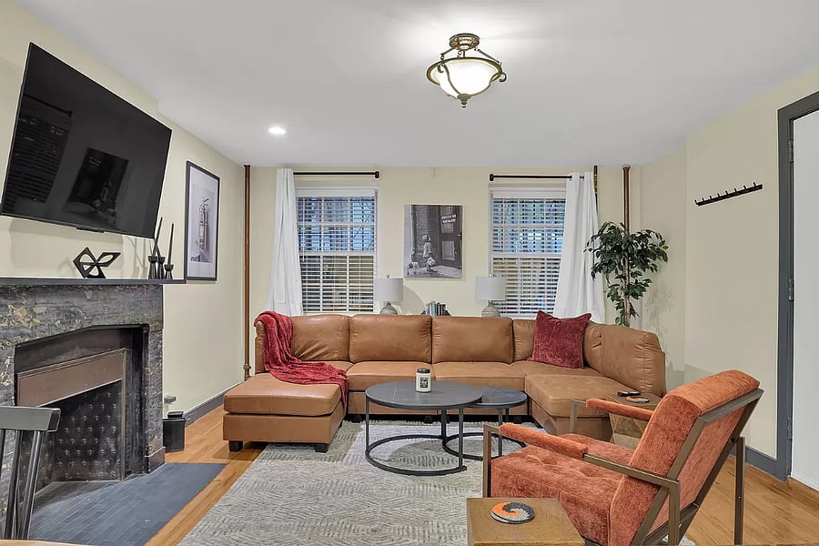 This living room boasts a sleek and spacious design with a large, comfortable couch that invites you to kick back and relax. With plenty of seating and a cozy fireplace, its perfect for movie nights on the smart TV or casual gatherings in an open-concept layout.