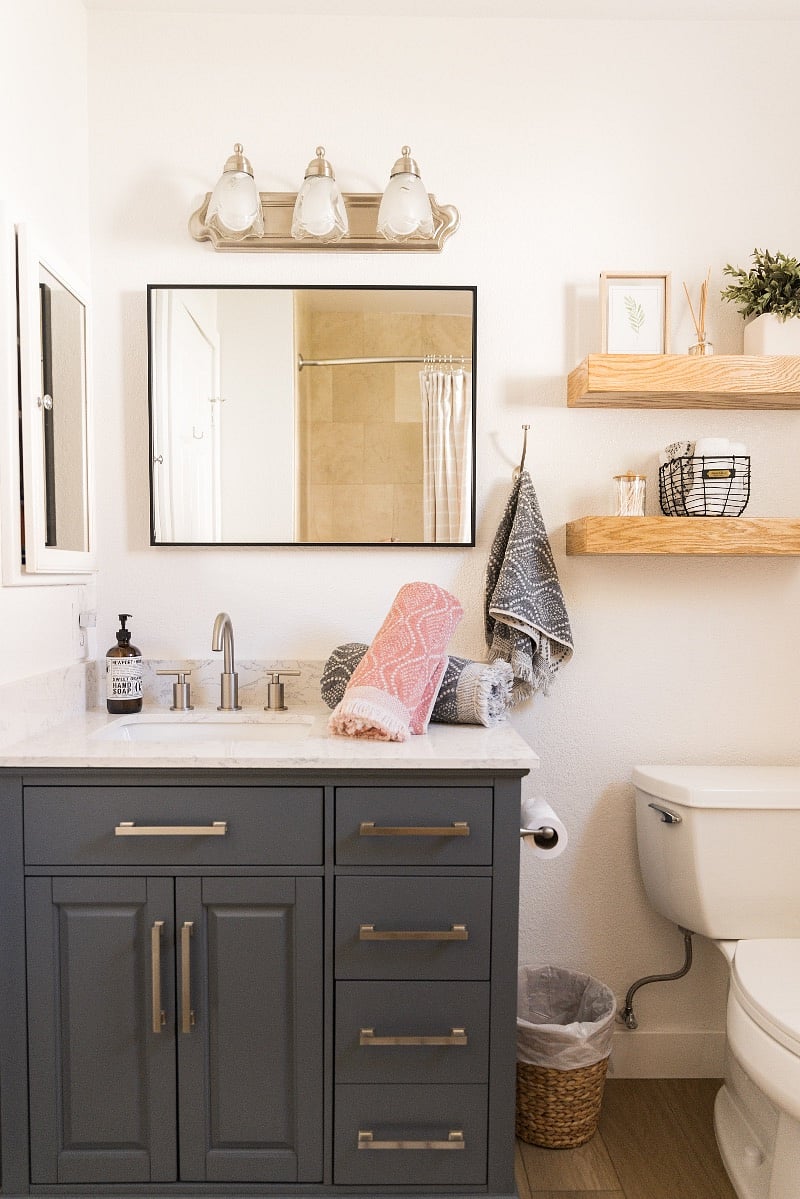 Newly remodeled hall bathroom has fresh clean vanity with beautiful wood shelving