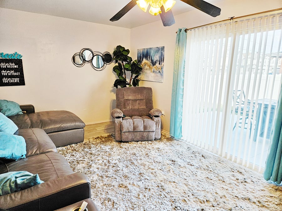 super bright Living space with reclining heat massage chair. Comfortable reclining sofas on both end of sectional. Cup holders and USB lines on furniture. Access to patio.