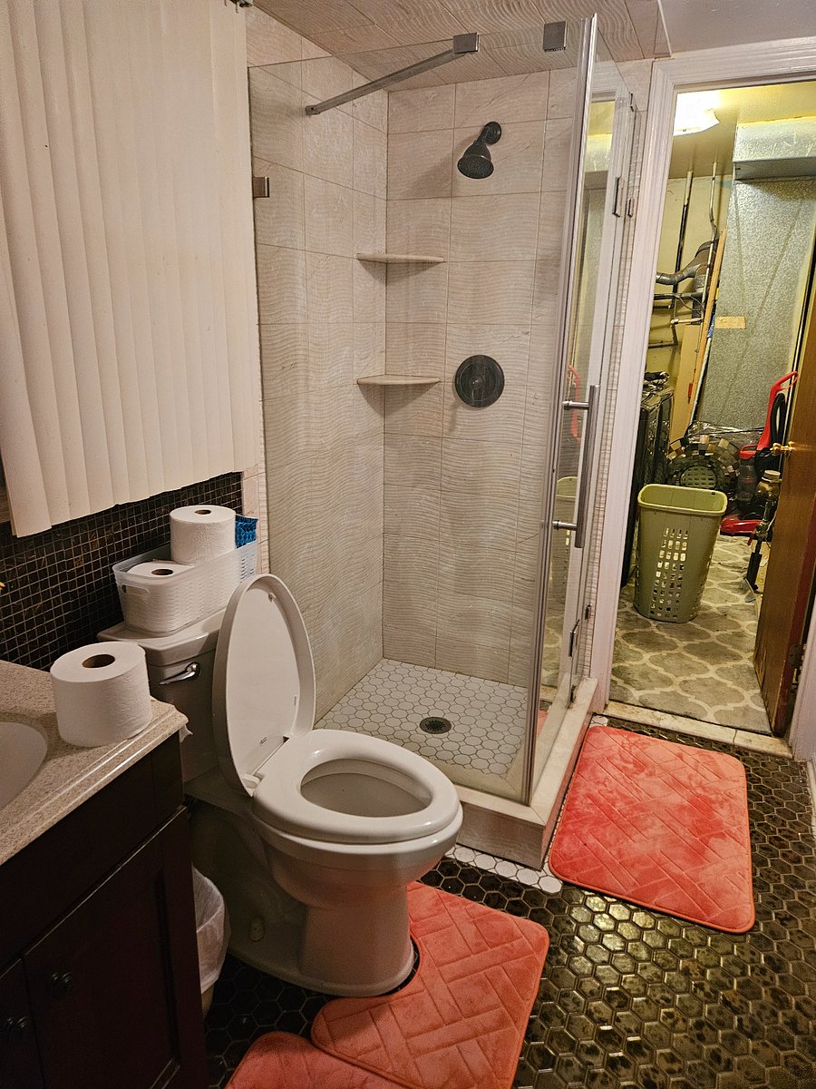 Beige bathroom with glass shower goes directly to laundry room as needed