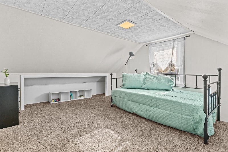 second floor space (lower ceiling height)  with day bed, small dresser and garment rack for extra clothes storage