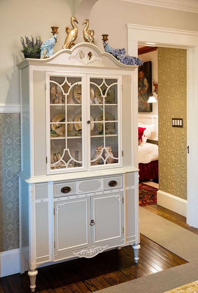 Antique, hand-painted china cabinet with bird-themed curiosities.
