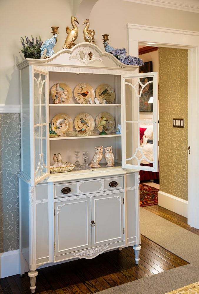 Antique, hand-painted china cabinet with bird-themed curiosities.