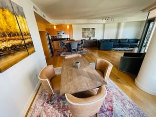 Dining table for dinners just off the kitchen and in the back you can see the shades pulled down and the sectional sofa in the TV area b y the window