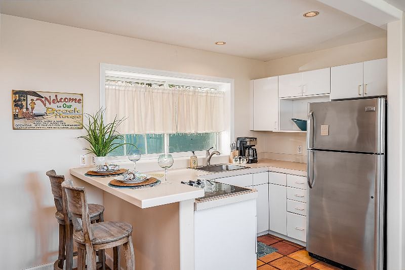Kitchen with stove top, full sized refrigerator and microwave. 

