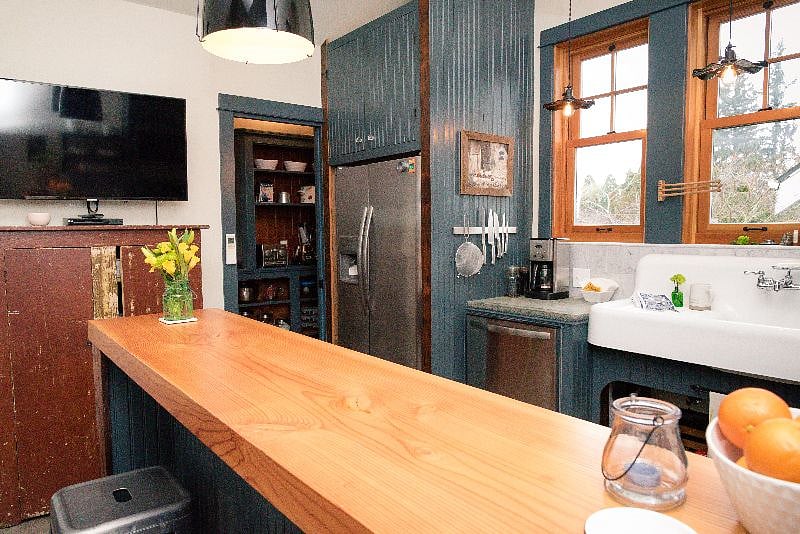First of two smart TVs (the 2nd is in the bedroom), wall-mounted for viewing from kitchen, dining bar, and living room.  American primitive antique armoire beneath to store work and study supplies, or can easily be swapped out for a table and chairs, in accordance with your needs and preferences.