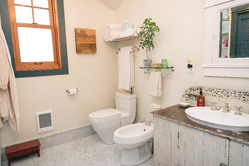 The bath is spacious, tiled in Carrera marble throughout, and features a bidet and an American Primitive antique buffet fitted for use as the vanity. 