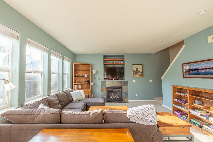 great room with entire wall of windows, L-shaped sectional, gas fireplace, smart TV, DVD player, and large collection of games and puzzles for your use