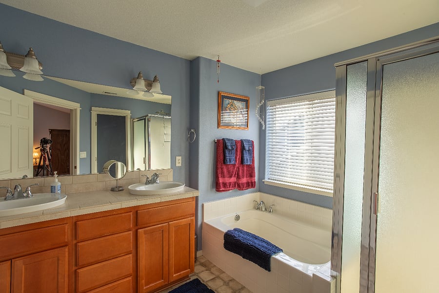 main bathroom with double sinks, soaker tub, shower, and separate toilet room