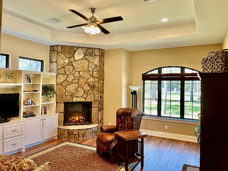 Living room with electric fireplace for ambiance and/or heat. Built-in bookcases, lots of windows, ceiling fan