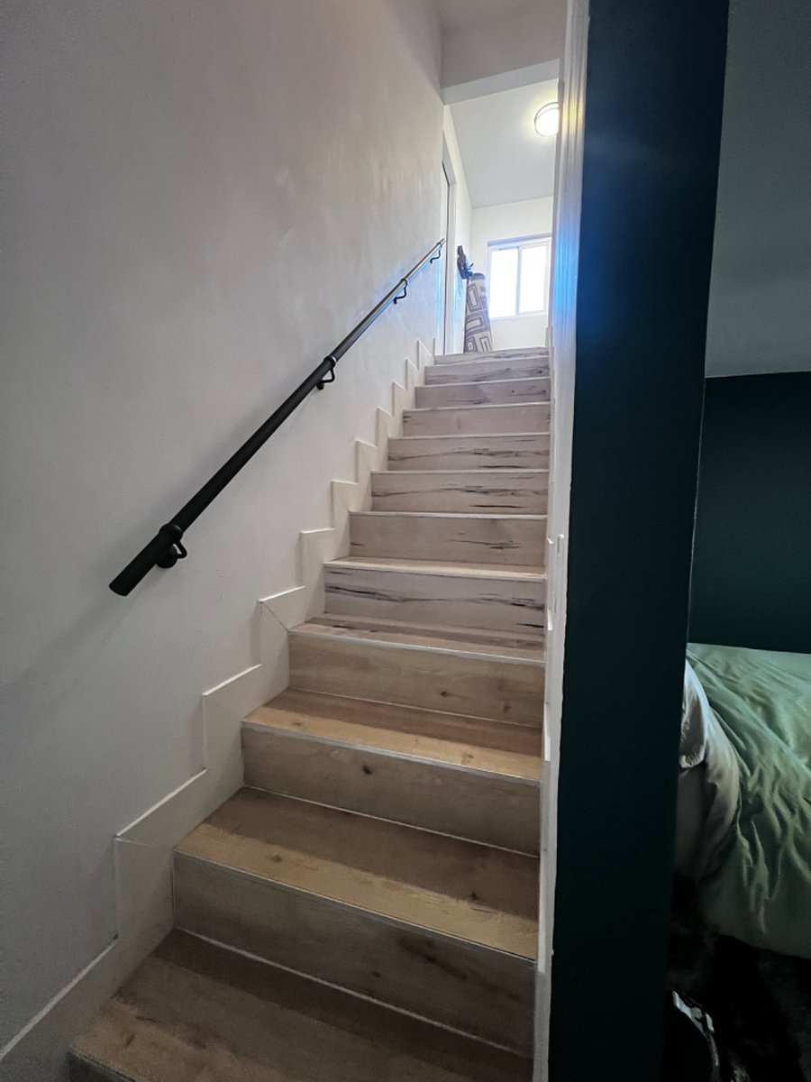 Stairs behind the bed leading to the garage where shared washer and dryer is.