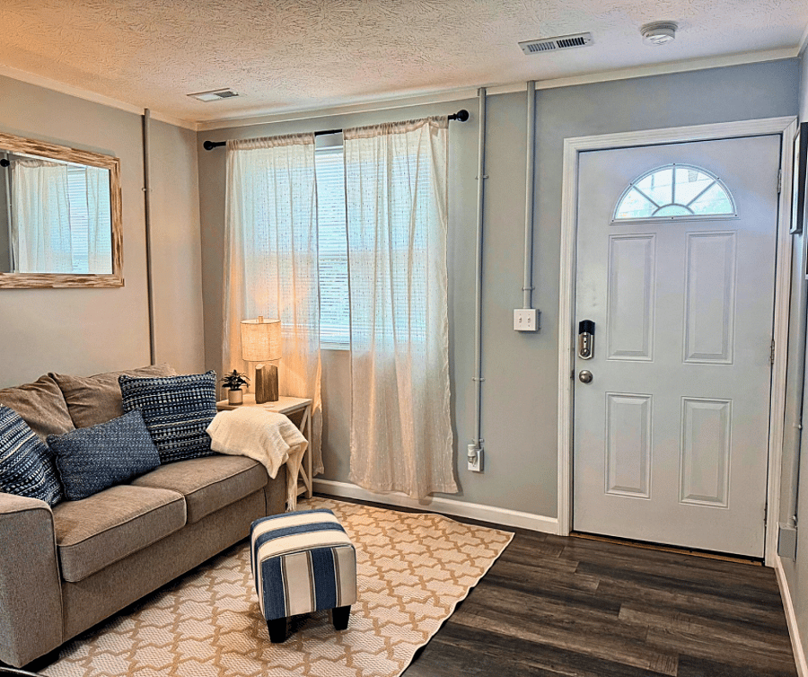 Bright and welcoming living space with smart lock entry, natural light, and cozy seating- perfect for relaxation after a long day.
