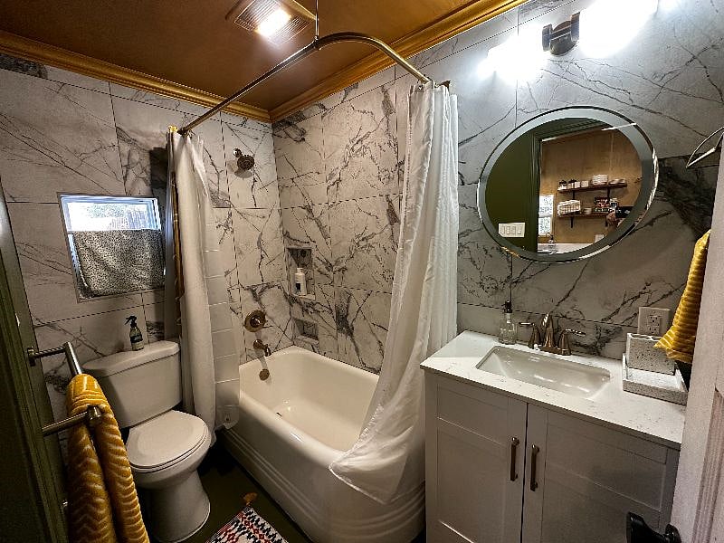 Featuring a refinished curved antique corner tub, large vanity, fresh new towels, back lit mirror with built in bluetooth speaker.
