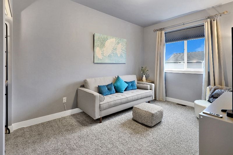 Modern media room with a plush foot rest, white leather accent chair, blankets, and a workstation with desk.