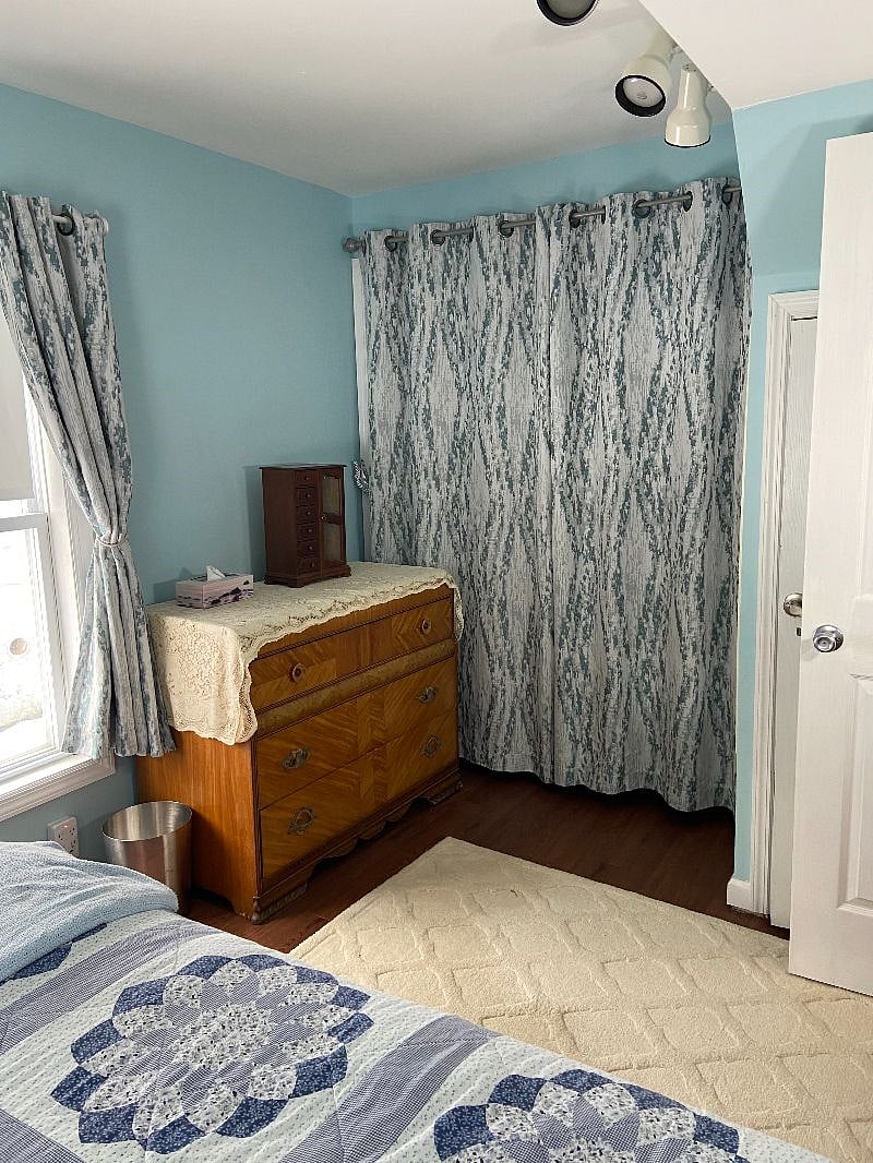 There is a closet behind the curtains with an additional dresser and linens.