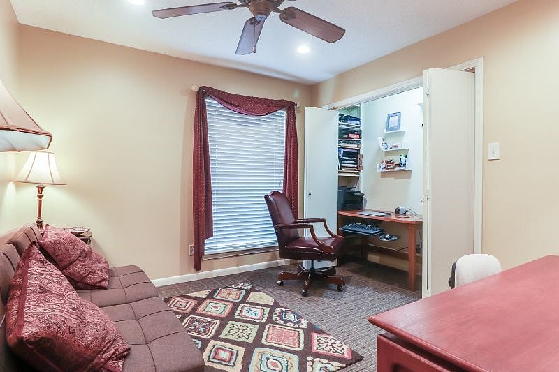 Closet doors in office open to reveal, desk, printer and office supplies.